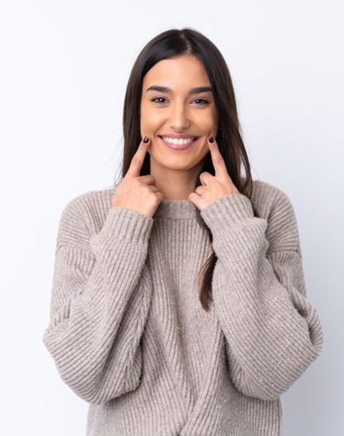 Happy young woman pointing at her smile