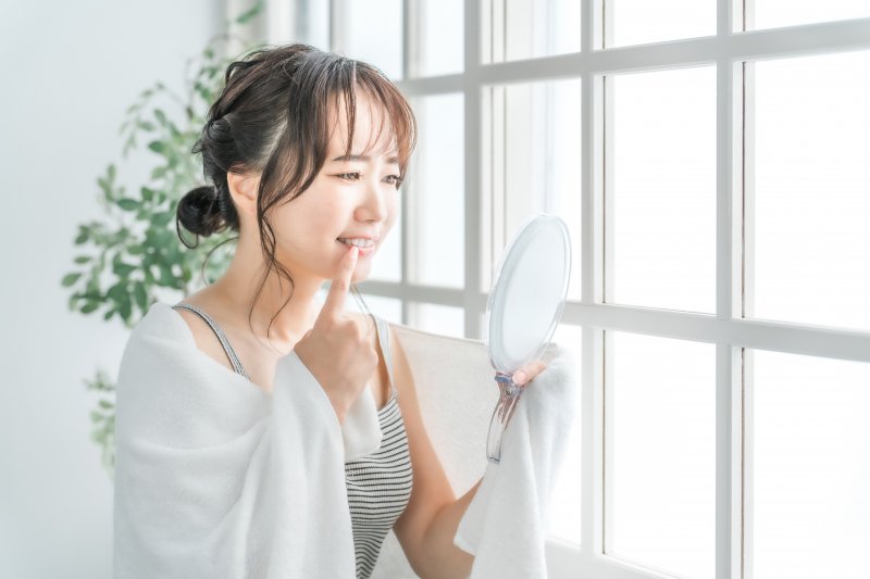 a woman checking her gums with a mirror